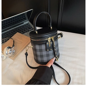 Close-up of diamond lattice cylinder bag with gold hardware and top handle detail