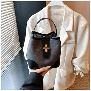 Close-up of retro bucket bag with charcoal suede fabric and gold metal swivel lock detail