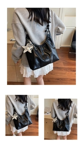 Detail view of large black crossbody bag with pleats and silver star charm accessory