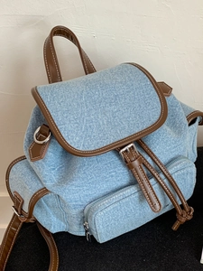 Minimalist light blue denim backpack with leather trim and contrasting white stitching