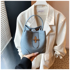 Detail of light blue bucket bag with gold metal clasp and soft matte leather texture