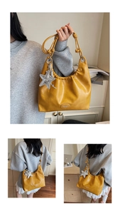 Detail of a bright yellow ruched shoulder bag featuring silver star charm and knotted strap