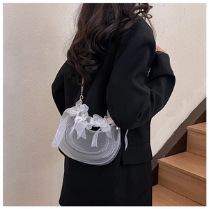 Detail of grey crescent bag with white lace bows and elegant metal chain strap