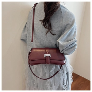 Macro shot of bordeaux leather baguette bag featuring a silver H-shaped metallic clasp