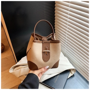 Detail of khaki wool bucket bag with brown leather patches and gold twist lock