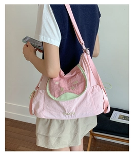 Detail view of pink watermelon crossbody bag with green pocket and adjustable strap