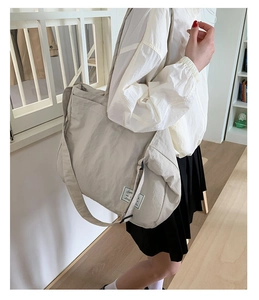 Versatile off-white canvas crossbody tote bag worn by model in a minimalist setting