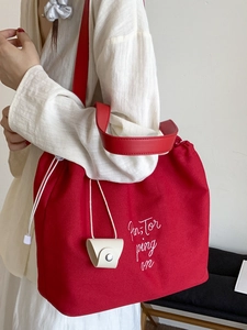 Red canvas drawstring bucket bag with Pan-Tor embroidery and wide shoulder strap