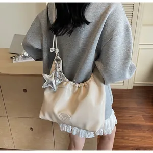 Detail of beige pleated hobo bag with silver star pendant and sleek leather logo patch