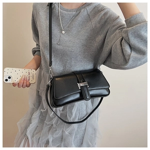Close-up of minimalist black faux leather shoulder bag with silver hardware and strap detail