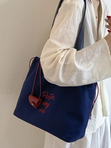 Dark blue canvas tote bag with red embroidery and drawstring closure for daily commute