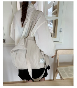 Detailed side view of the off-white canvas tote bag featuring a woven brand label