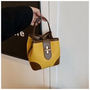 Detail view of contrast color bucket bag with yellow suede and brown leather trim