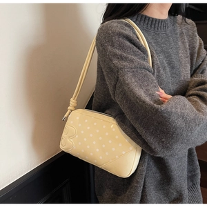 Close-up of pale yellow shoulder bag with white polka dots and B-shaped detail