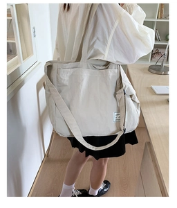 Spacious beige canvas tote bag shown on model with adjustable strap and wide handles
