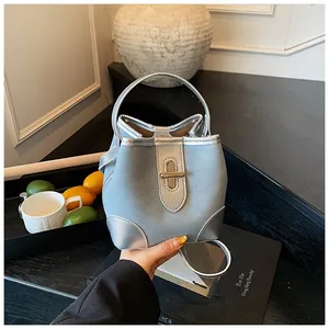 Detail of light blue bucket bag with silver clasp and metallic handle on a table