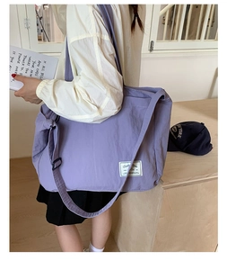 Detail of purple canvas tote bag with adjustable wide strap and decorative white fabric label