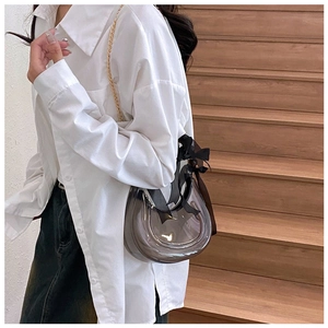 Detail of translucent gray crescent bag with black chiffon bow and gold metal chain strap
