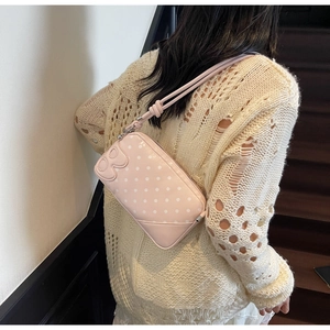 Pink polka dot shoulder bag featuring embossed letter B and knotted strap detail
