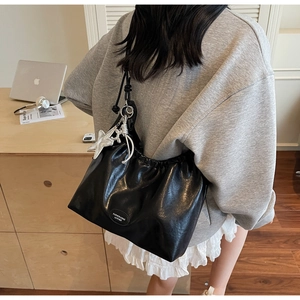 Detail of black pleated shoulder bag with starfish charm worn by model in casual setting