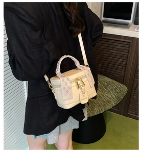 Detail of cream bucket bag with silk scarf wrapped handle and branded hangtag