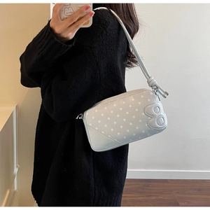 Detail of light blue polka dot shoulder bag with knot strap and 3D relief decor