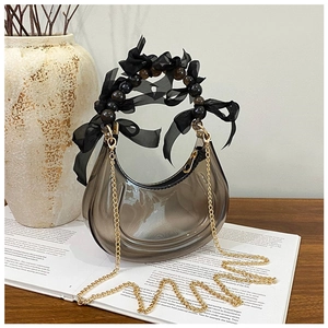 Detail view of crescent bag with beaded handle, ribbon and golden chain strap