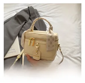 Detail of cream vanity bag with checkered silk scarf wrap and gold-tone metal hardware