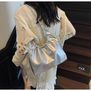 Detail of silver metallic puffy shoulder bag with star charm and knotted strap design