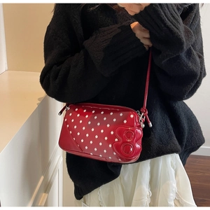 Close-up of red polka dot shoulder bag with glossy patent leather and 3D detail