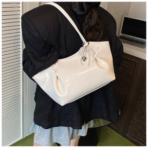 Détail d'un sac cabas blanc brillant avec plis et charm cœur en perles décoratif