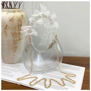 Detailed macro of transparent crescent bag with beaded handle and white organza bow