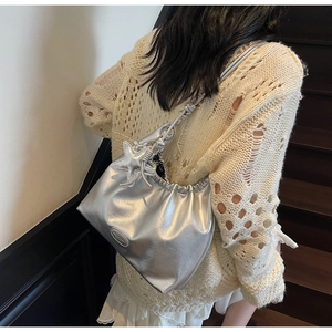 Detail view of silver metallic tote bag with star charm and pleated texture details