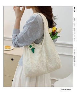 Lace tote bag detail showing intricate floral crochet and green flower charm
