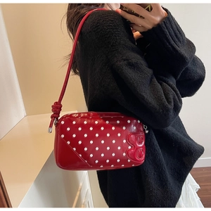 Close-up of red polka dot patent leather shoulder bag with embossed letter B detail
