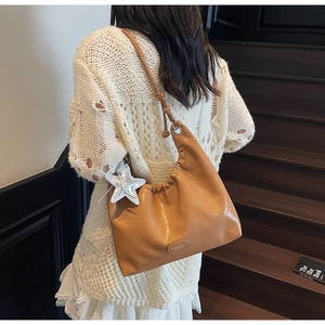 Detail of caramel pleated shoulder bag with silver glitter star charm and tied strap