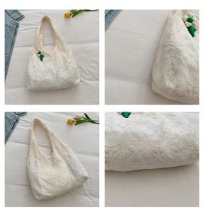Detail of white lace tote bag with floral embroidery and green center flower pendant