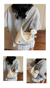 Détail d'un sac hobo crème avec papillons argentés et pendentif nuage en peluche