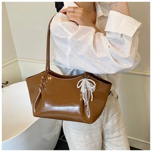 Gros plan du sac cabas marron brillant avec pendentif noeud en dentelle et perles raffiné
