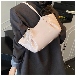Détail d'un sac d'épaule en cuir verni rose avec perles et nœuds en dentelle
