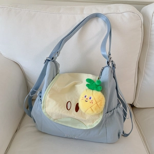 Detail view of light blue nylon backpack with cute cartoon face and pineapple plush charm