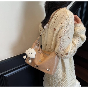 Détail du sac bandoulière plissé marron clair avec papillon en métal et breloque en peluche