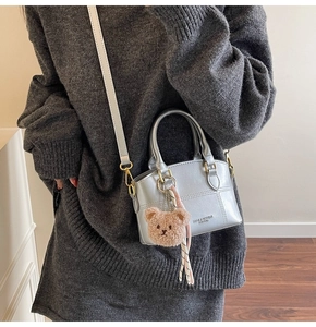 Detailaufnahme einer silbernen Mini-Handtasche mit Metall-Finish und süßem Teddy-Anhänger