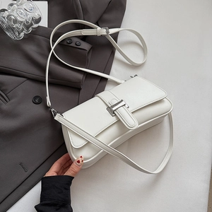 Detail of white leather baguette bag with silver metal buckle on grey blazer