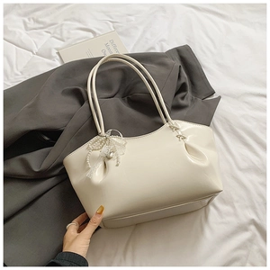 Détail du sac cabas en cuir blanc cassé avec nœud en dentelle et perles sur le côté