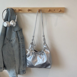Detail of silver metallic tote bag featuring star charm, pleated top and cord strap