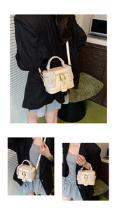 Detail of a cream bucket bag featuring a silk-wrapped handle and gold zipper hardware
