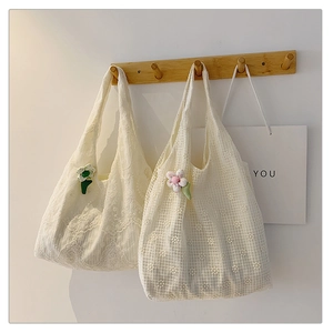 Detailed close-up of white lace and mesh tote bags with floral embroidery and cute pendants