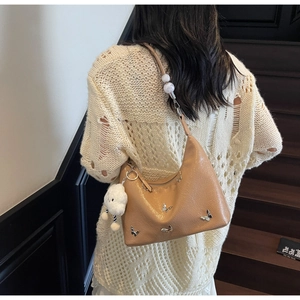 Détail d'un sac hobo marron avec breloques papillon en argent et nuage en peluche doux