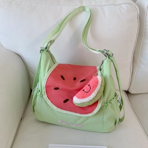 Detail of a watermelon themed shoulder bag with green canvas and embroidered text